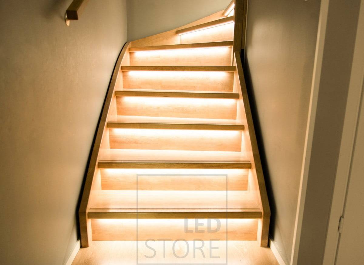Escalera de madera iluminada por tiras de leds en los peldaños, montadas en el borde de la escalera